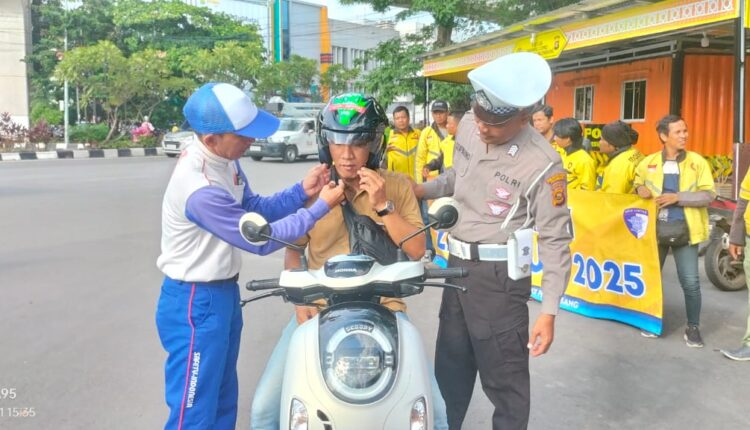 Kasatlantas Polrestabes Palembang AKBP Finan S Radipta saat memasangkan helm ke pengendara.