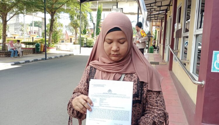 Mareta Sinta (35) menunjukkan surat bukti laporan kepolisian usai mendatangi Sentra Pelayanan Kepolisian Terpadu (SPKT) Polrestabes Palembang.