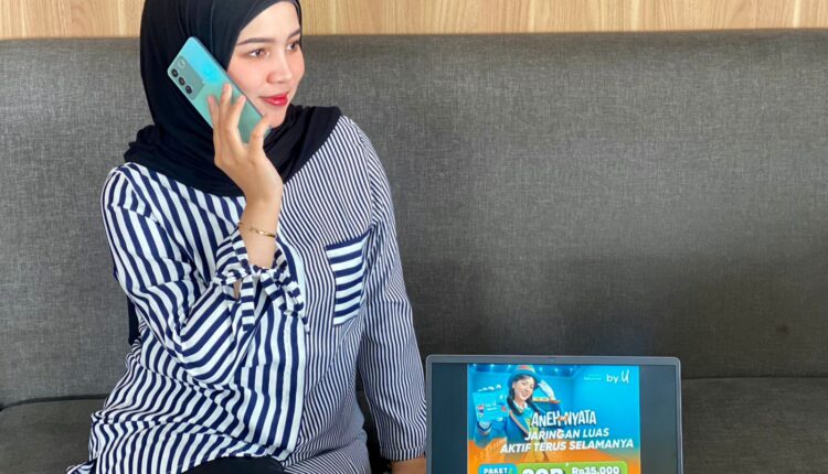 Seorang pelanggan sedang melakukan panggilan telepon seluler di dekat laptop yang menampilkan informasi promo Paket Super Kaget dari by.U di Palembang.