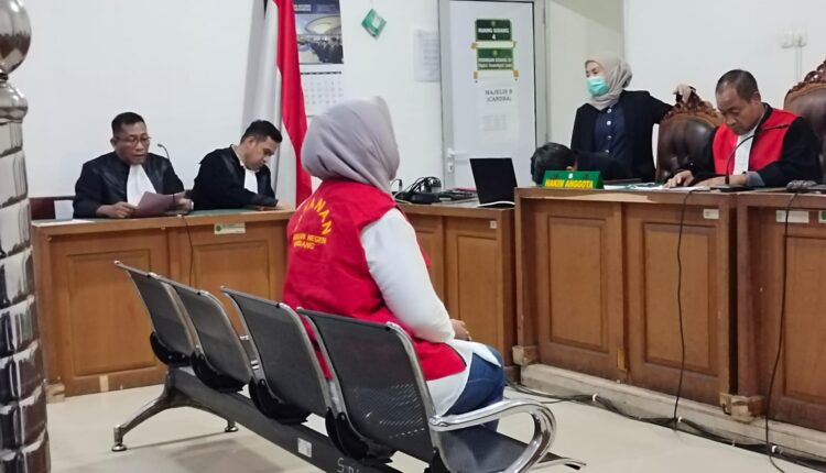 Terdakwa Kurniati Hasda Ayu (mengenakan rompi tahanan) mendengarkan pembacaan surat dakwaan oleh Jaksa Penuntut Umum (JPU) Romi Pasolini dalam sidang perdana kasus dugaan penggelapan di Pengadilan Negeri (PN) Palembang, Sumatera Selatan. 