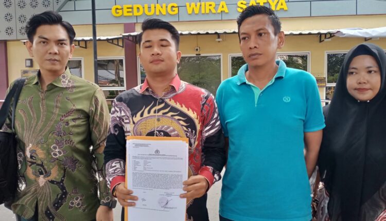 Kuasa hukum korban, Febri Ardiansyah, menunjukkan berkas laporan polisi didampingi kliennya, Ibrahim, di depan Gedung Wira Satya SPKT Polrestabes Palembang, Sumatra Selatan.