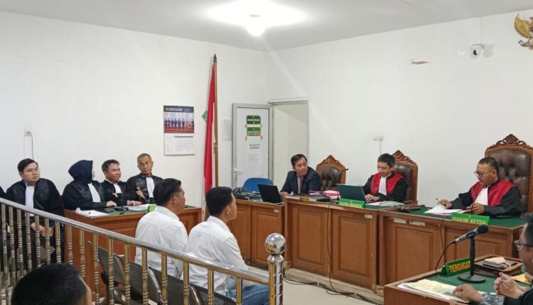 Terdakwa Kholizol Tamhullis (duduk di kursi pesakitan, kiri) dan anaknya, Raga Alan Sakti (duduk di kursi pesakitan, kanan), mendengarkan pembacaan surat dakwaan oleh Jaksa Penuntut Umum (JPU) dalam sidang perdana yang dipimpin Ketua Majelis Hakim Idil Amin di Pengadilan Tindak Pidana Korupsi (Tipikor) pada Pengadilan Negeri Palembang, Sumatera Selatan.