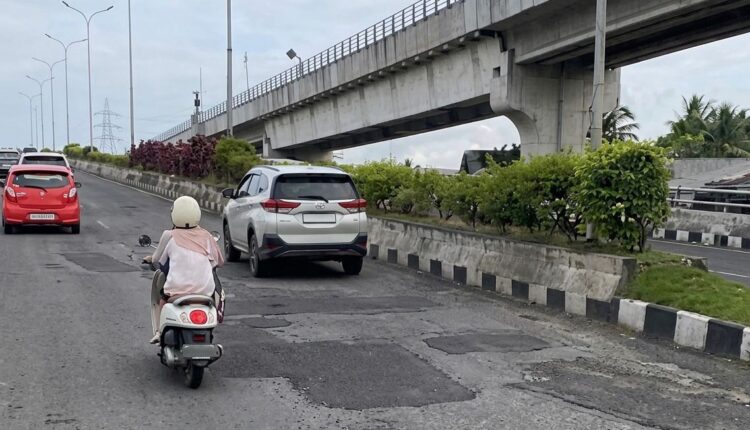 Pengendara sepeda motor dan mobil melintasi Jalan Gubernur H.A. Bastari, Kecamatan Jakabaring, Palembang yang kondisinya dipenuhi bekas tambalan dan bergelombang di Kota Palembang.
