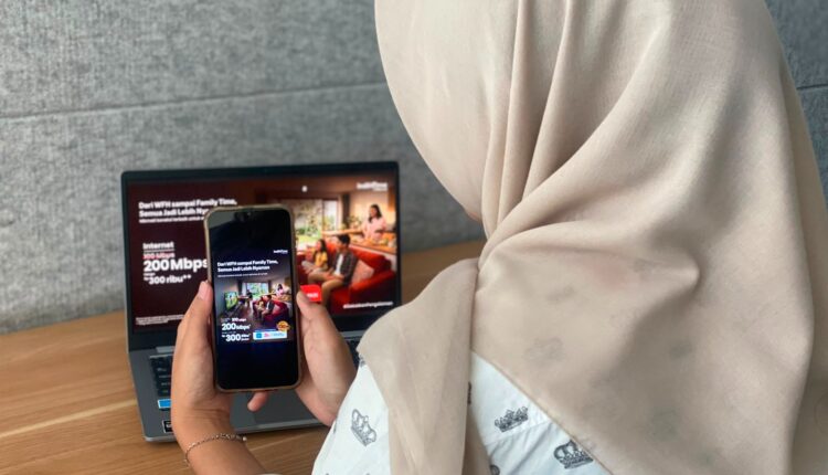 Seorang pelanggan di wilayah Sumatera Bagian Selatan (Sumbagsel) sedang mengakses informasi promo peningkatan kecepatan internet IndiHome dari 100 Mbps menjadi 200 Mbps melalui perangkat telepon genggam dan laptop.