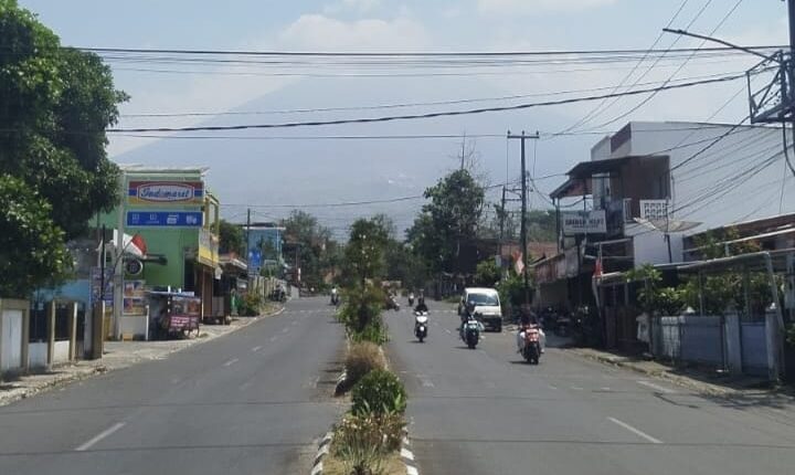 Suasana arus lalu lintas di salah satu jalan utama Kota Pagar Alam dengan latar belakang pegunungan yang tampak samar terhalang lapisan asap tipis.