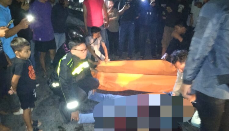 Sejumlah petugas kepolisian dan warga mengevakuasi jenazah korban kecelakaan lalu lintas di Jalan RE Martadinata, seberang Kantor Badan Gizi Nasional Kota Palembang.