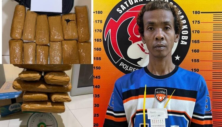 Tersangka kurir narkoba berinisial HF (38) berdiri di samping barang bukti 12 paket ganja kering seberat total 7,2 kilogram saat diamankan di Mapolres Pagar Alam, Sumatra Selatan.