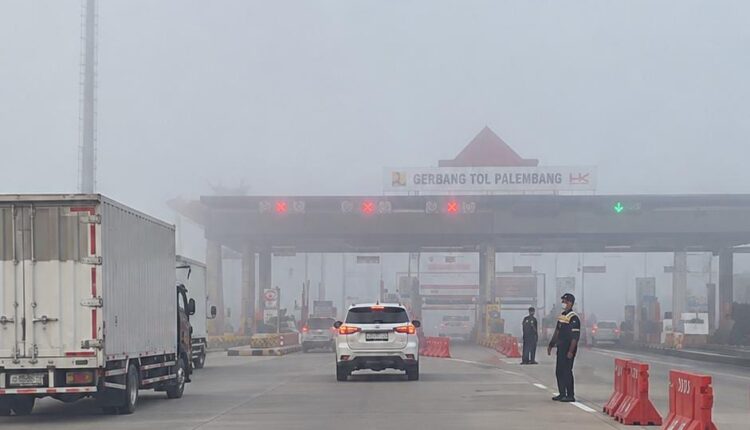 Sejumlah kendaraan mengantre saat melintasi Gerbang Tol Palembang yang diselimuti kabut tebal.