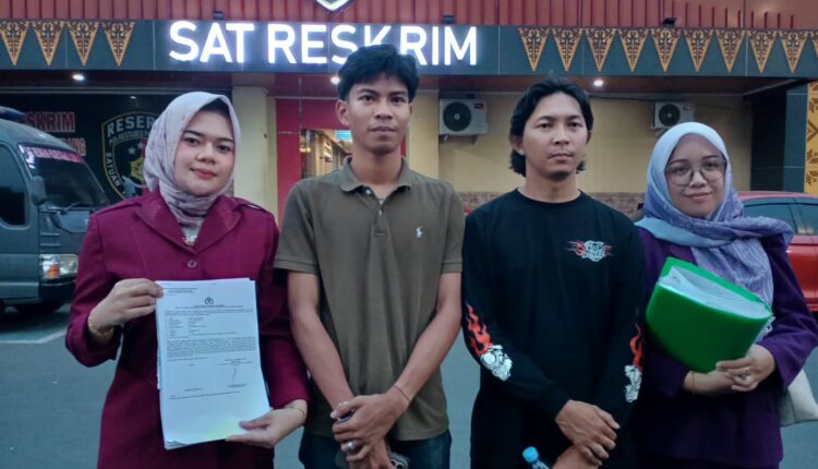 Pelapor Ahmad Alfiansyah didampingi Kuasa Hukum dari LBH Bima Sakti, Indah Permatasari, dan Ines, menunjukkan bukti laporan saat berada di depan gedung Sat Reskrim Polrestabes Palembang.