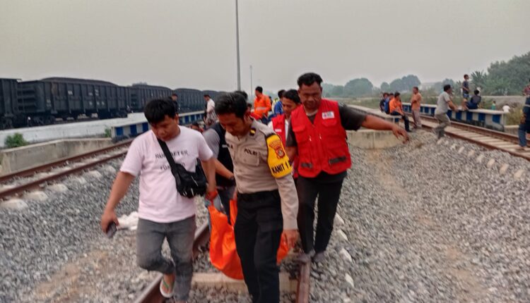 Petugas kepolisian dari Polrestabes Palembang bersama warga mengepaki dan mengevakuasi jenazah Nasrulpa (64) yang tewas setelah tertabrak kereta api di perlintasan KM Said, Kelurahan Karya Jaya, Kecamatan Kertapati, Palembang.