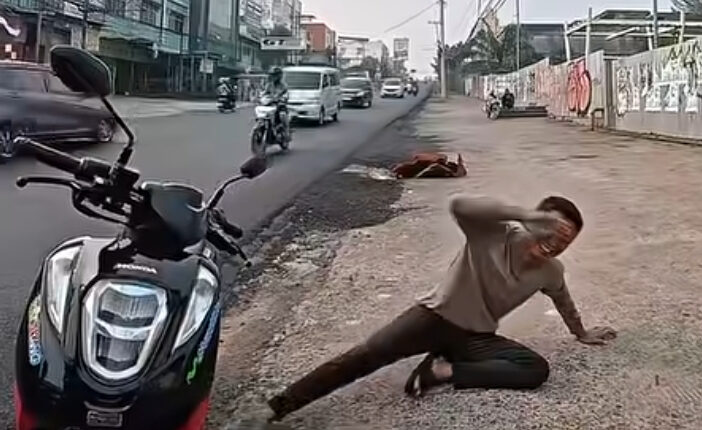 Seorang pengendara sepeda motor terduduk di pinggir jalan sambil berakting menangis saat dihentikan oleh anggota Satlantas Polrestabes Palembang.