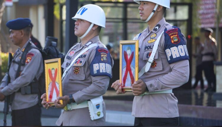 Dua foto anggota Brimob Polda Sumsel yang diberhentikan secara tidak hormat dicoret memakai cat pilox.