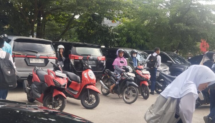 Orang tua siswa/i menjemput anaknya di halaman SMPN 19 Palembang.