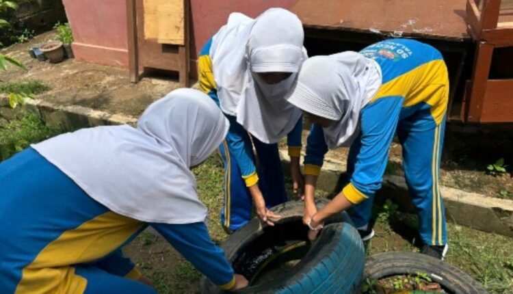 Sejumlah siswa sedang membersihkan genangan air di ban bekas di wilayah sekolah. (Foto: Ist)
