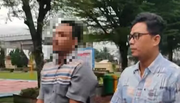 Tersangka MF (48), mengenakan kemeja motif garis, saat diamankan di Polrestabes Palembang.