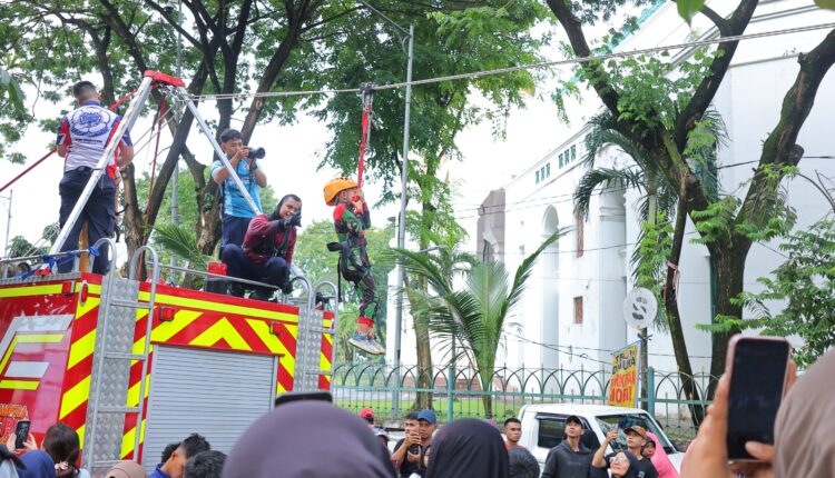 Seorang anak dengan pengamanan lengkap mencoba wahana flying fox gratis yang disediakan oleh Dinas Pemadam Kebakaran (Damkar) Kota Palembang dalam kegiatan Car Free Day (CFD).