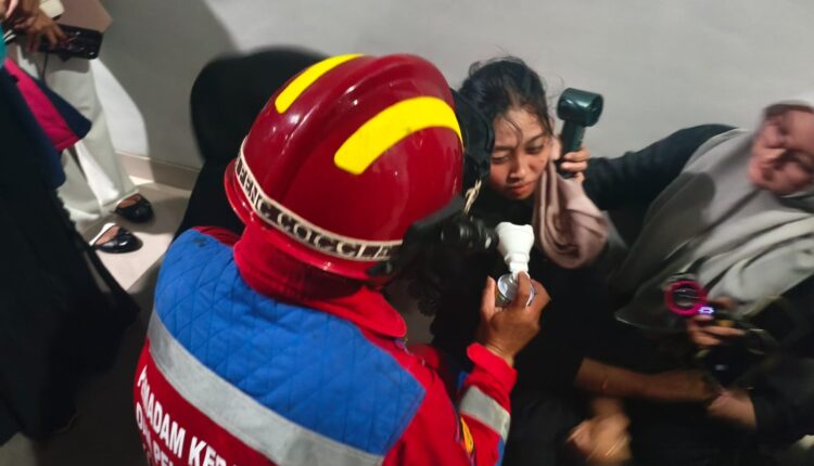 Petugas Ampera Fire Rescue Dinas Pemadam Kebakaran dan Penyelamatan Kota Palembang memberikan bantuan pernapasan menggunakan tabung oksigen portabel kepada seorang mahasiswi Universitas Muhammadiyah Palembang (UMP) yang syok usai dievakuasi di gedung Fakultas Ekonomi UMP, Palembang.