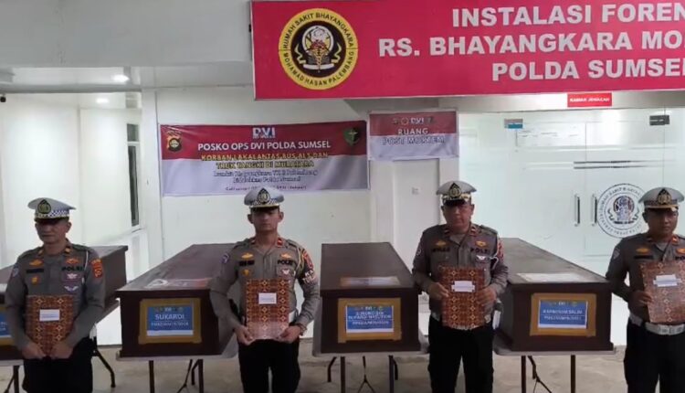 Sejumlah anggota kepolisian berdiri di depan peti jenazah saat konferensi pers penyelesaian identifikasi korban kecelakaan maut di Instalasi Forensik RS Bhayangkara Moh Hasan Polda Sumsel, Palembang.