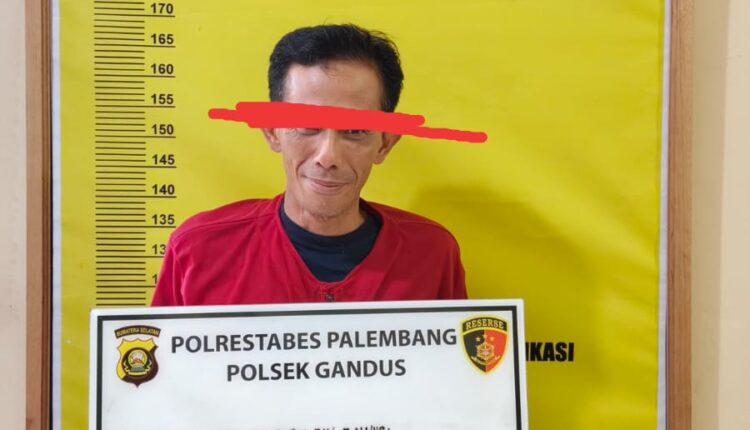 Tersangka Indra Gunawan (46) menunjukkan papan identitas perkara di Mapolsek Gandus, Palembang, Sumatera Selatan.