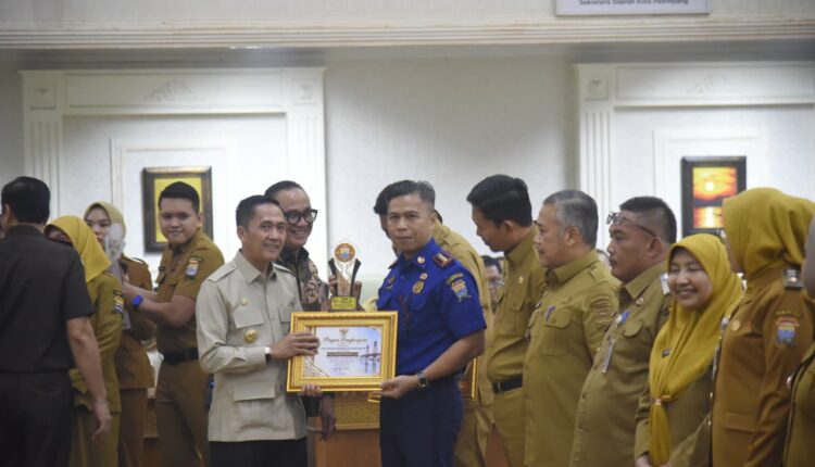 Wali Kota Palembang Ratu Dewa menyerahkan trofi dan piagam Penghargaan Hasil Penilaian Evaluasi Kinerja Penyelenggaraan Pelayanan Publik (PEKPPP) Mandiri Tahun 2026 kepada perwakilan instansi berprestasi di Ruang Parameswara, Sekretariat Daerah Kota Palembang.